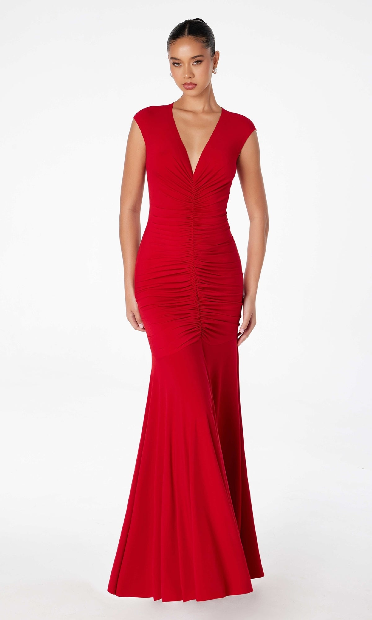 A woman models the Cap-Sleeve Long Ruched Prom Dress: Astee T2009, a floor-length red gown with fitted cap sleeves and a deep V-neckline, standing against a plain white background.